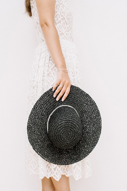 Jeune jolie femme en robe blanche avec chapeau noir