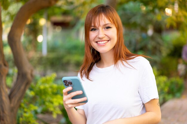 Jeune jolie femme rousse à l'extérieur à l'aide d'un téléphone portable