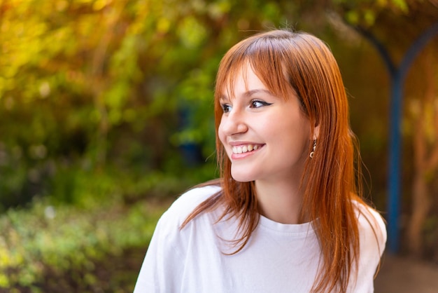 Jeune jolie femme rousse à l'extérieur avec une expression heureuse