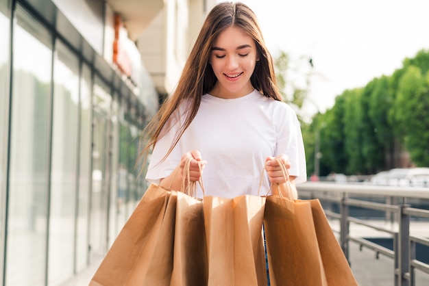 Jeune jolie femme avec des sacs à provisions marchant sur la rue de la ville