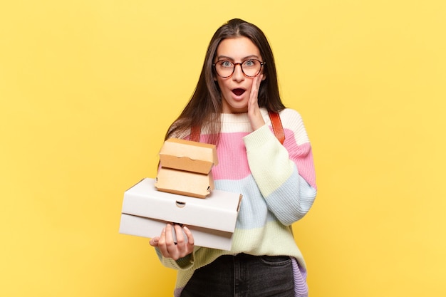 Jeune jolie femme se sentant choquée et effrayée, l'air terrifiée avec la bouche ouverte et les mains sur les joues. prenez un concept de restauration rapide