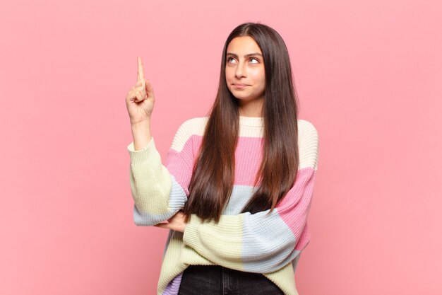 Jeune jolie femme se sentant comme un génie tenant le doigt fièrement en l'air après avoir réalisé une excellente idée, disant eureka