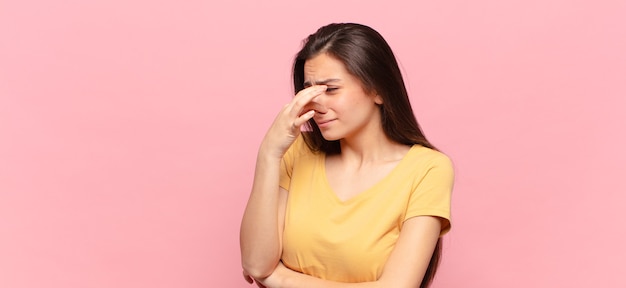 Jeune jolie femme se sentant dégoûtée, tenant le nez pour éviter de sentir une odeur nauséabonde et désagréable