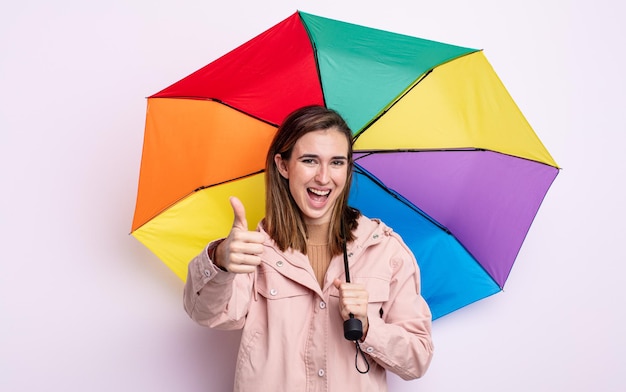 Jeune jolie femme se sentant fière, souriante positivement avec les pouces vers le haut. concept de parapluie