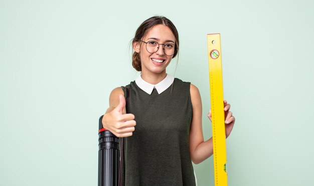 Jeune jolie femme se sentant fière, souriante positivement avec les pouces vers le haut. notion d'architecture