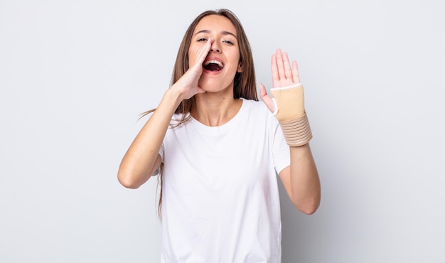 Jeune jolie femme se sentant heureuse, donnant un grand cri avec les mains à côté de la bouche. concept de bandage à la main