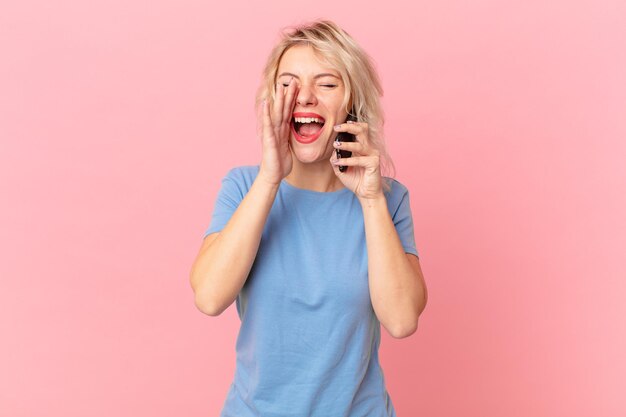 Jeune jolie femme se sentant heureuse, donnant un grand cri avec les mains à côté de la bouche. notion de cellule