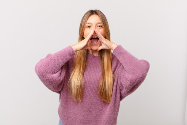 Jeune jolie femme se sentant heureuse, donnant un grand cri avec les mains à côté de la bouche