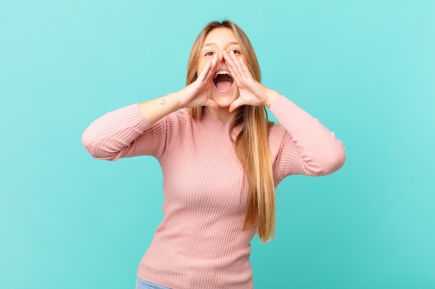 Jeune jolie femme se sentant heureuse, donnant un grand cri avec les mains à côté de la bouche