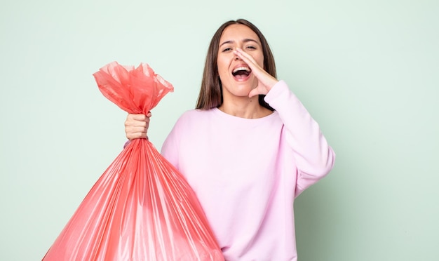 Jeune jolie femme se sentant heureuse en donnant un grand cri avec les mains à côté du concept de poubelle buccale