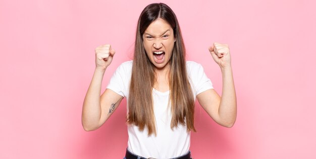 Jeune jolie femme se sentant heureuse, surprise et fière, criant et célébrant le succès avec un grand sourire