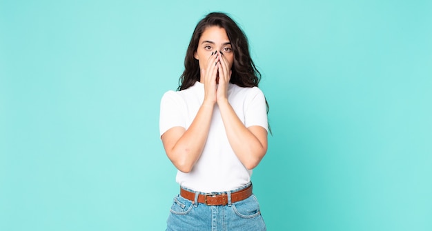 Jeune jolie femme se sentant inquiète, contrariée et effrayée, couvrant la bouche avec les mains, l'air anxieuse et ayant foiré