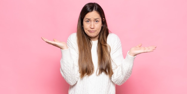 Jeune jolie femme se sentant perplexe et confuse, doutant, pondérant ou choisissant différentes options avec une expression amusante