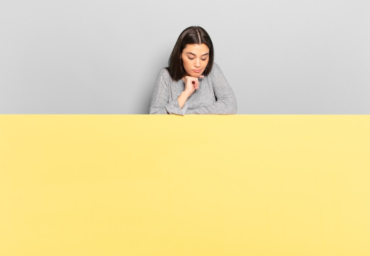 Photo jeune jolie femme se sentant réfléchie, se demandant ou imaginant des idées, rêvant et levant les yeux pour copier l'espace