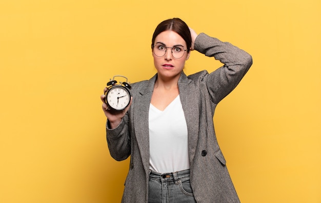 Jeune jolie femme se sentant stressée, inquiète, anxieuse ou effrayée, les mains sur la tête, paniquée par erreur