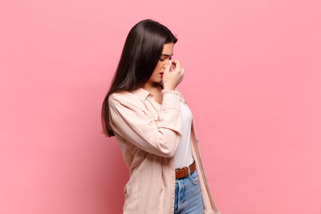 Jeune jolie femme se sentant stressée, malheureuse et frustrée, touchant le front et souffrant de migraine de maux de tête sévères