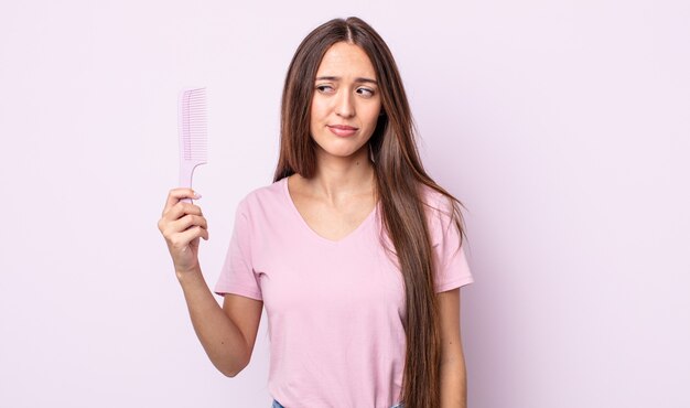 Jeune jolie femme se sentant triste, bouleversée ou en colère et regardant sur le côté. concept de peigne à cheveux