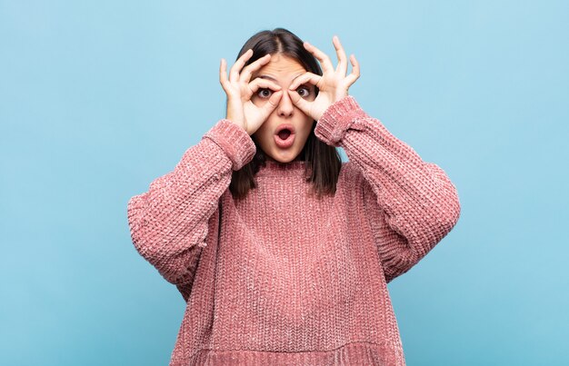 Photo jeune jolie femme se sentir choquée, étonnée et surprise, tenant des lunettes avec un regard étonné et incrédule