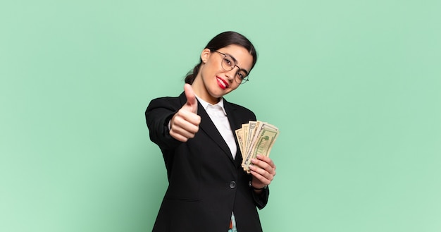 Jeune jolie femme se sentir fière, insouciante, confiante et heureuse, souriant positivement avec les pouces vers le haut