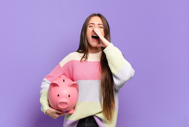 Jeune jolie femme se sentir heureuse, excitée et positive, donnant un grand cri avec les mains à côté de la bouche, appelant