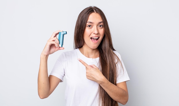 Jeune jolie femme semblant excitée et surprise en pointant sur le côté. concept d'asthme