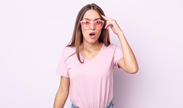 Jeune jolie femme semblant surprise, réalisant une nouvelle pensée, idée ou concept. concept de lunettes de soleil roses