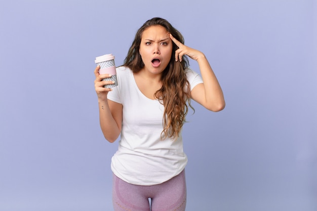 Jeune jolie femme semblant surprise, réalisant une nouvelle pensée, idée ou concept et tenant un café