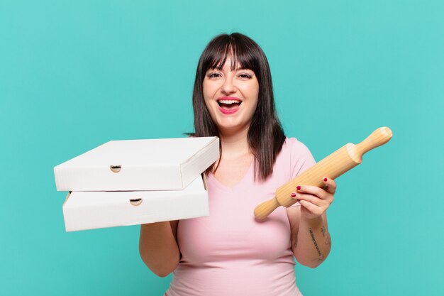 Jeune jolie femme sinueuse expression heureuse et tenant une pizza