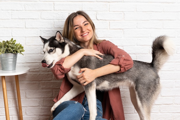 Jeune jolie femme avec son chien husky assis dans le sol à l'intérieur