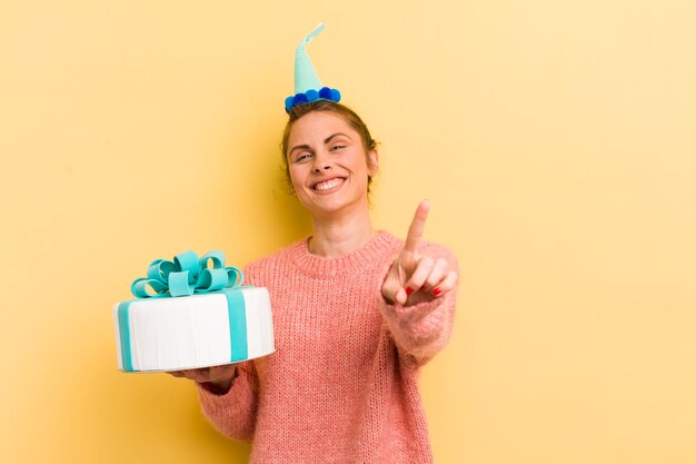 Jeune jolie femme souriant fièrement et en toute confiance faisant le concept d'anniversaire numéro un