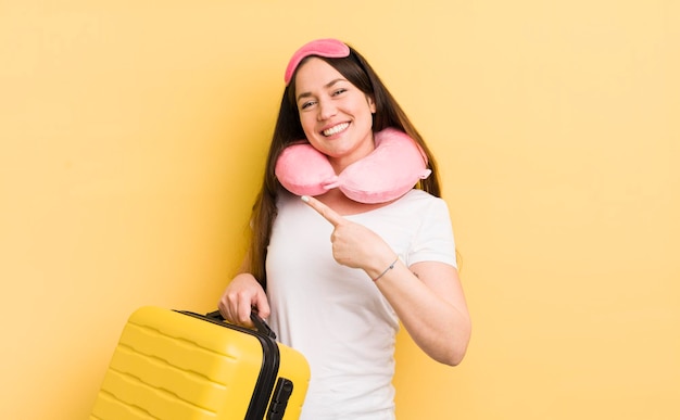 Jeune jolie femme souriant joyeusement se sentant heureuse et pointant vers le concept de passager de vol latéral