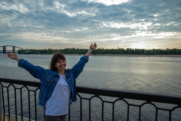 Jeune jolie femme souriante au bord de la rivière sur l'espace de copie du lever du soleil