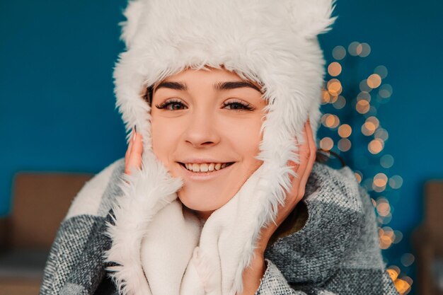 Jeune jolie femme souriante célébrant un pull chaud habillé et un bonnet de laine, debout posant