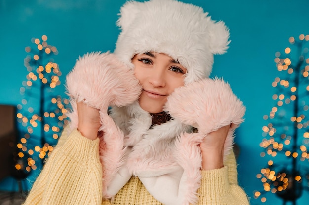 Jeune jolie femme souriante célébrant un pull chaud habillé et un bonnet de laine, debout posant