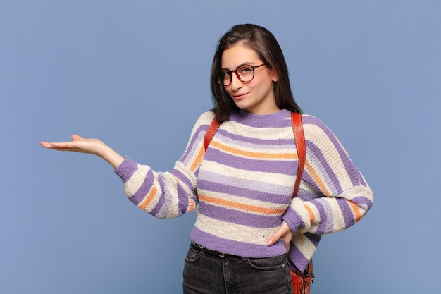 Jeune jolie femme souriante, confiante, réussie et heureuse, montrant un concept ou une idée sur l'espace de copie sur le côté. concept d'étudiant