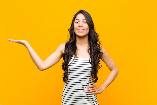 Jeune jolie femme souriante, confiante, réussie et heureuse, montrant quelque chose