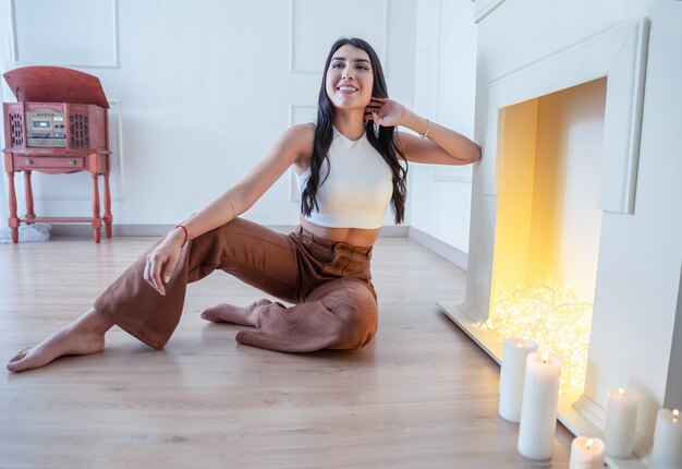 Photo jeune jolie femme souriante détendue assise sur le sol à la maison