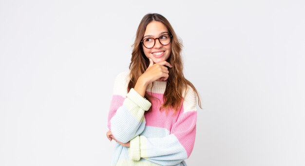 Jeune jolie femme souriante avec une expression heureuse et confiante avec la main sur le menton