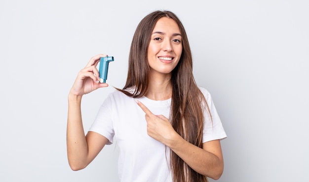 Jeune jolie femme souriante joyeusement, se sentant heureuse et pointant sur le côté. concept d'asthme