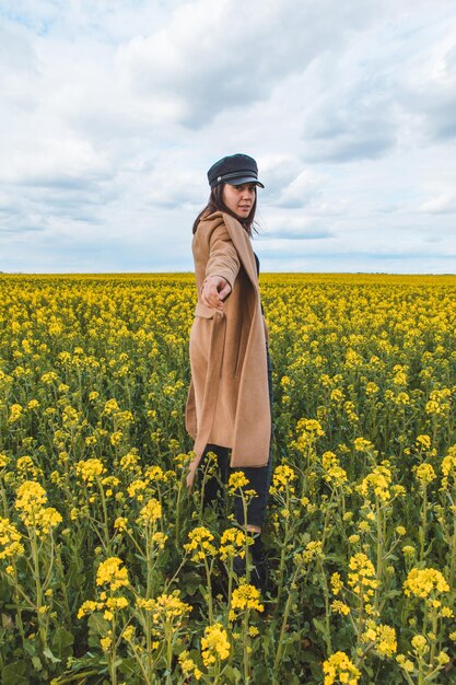 Jeune jolie femme souriante marchant dans un champ de colza jaune