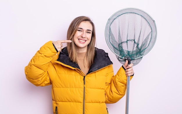 Jeune jolie femme souriante pointant avec confiance vers son propre large sourire. concept de pêcheur