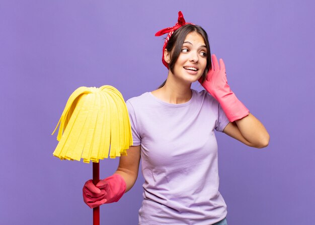 Jeune jolie femme souriante, regardant curieusement sur le côté, essayant d'écouter des potins ou d'entendre un secret