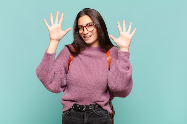 Jeune jolie femme souriante et sympathique, montrant le numéro dix ou dixième avec la main en avant, compte à rebours. concept d'étudiant