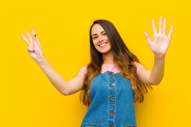 Jeune jolie femme souriante et sympathique, montrant le numéro neuf ou neuvième avec la main vers l'avant, compte à rebours