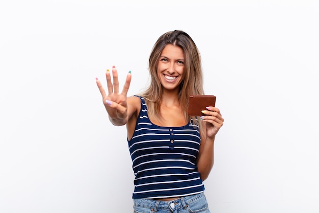 Jeune jolie femme souriante et sympathique, montrant le numéro quatre ou quatrième avec la main en avant, compte à rebours avec un portefeuille en cuir.