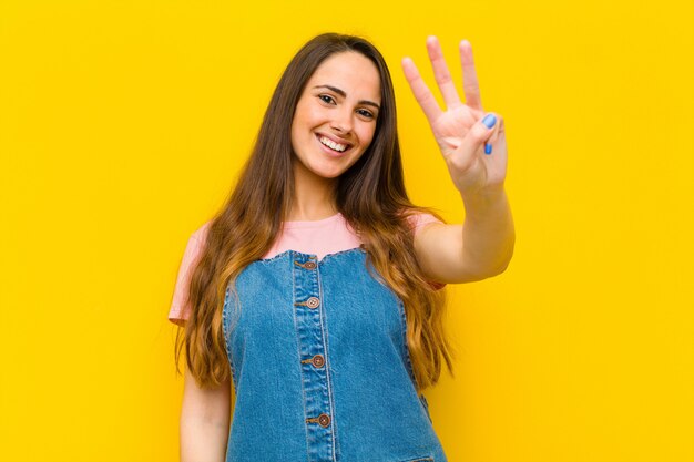 Jeune jolie femme souriante et sympathique, montrant le numéro trois ou troisième avec la main vers l'avant, compte à rebours