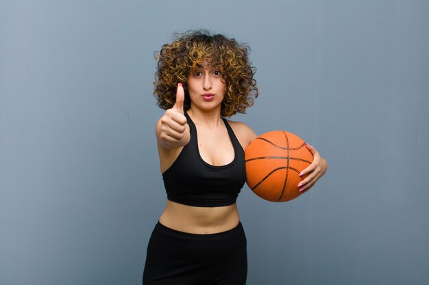 Jeune jolie femme sportive portant des vêtements de fitness avec un ballon de basket