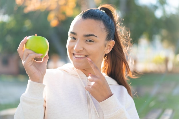Jeune jolie femme sportive tenant une pomme avec une expression heureuse