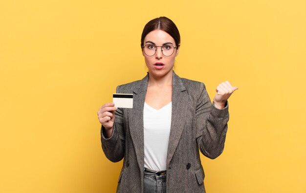 Jeune jolie femme à la stupéfaction, en pointant sur l'objet sur le côté et en disant wow, incroyable