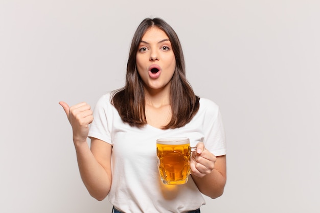 Jeune jolie femme a surpris l'expression et tenant une bière